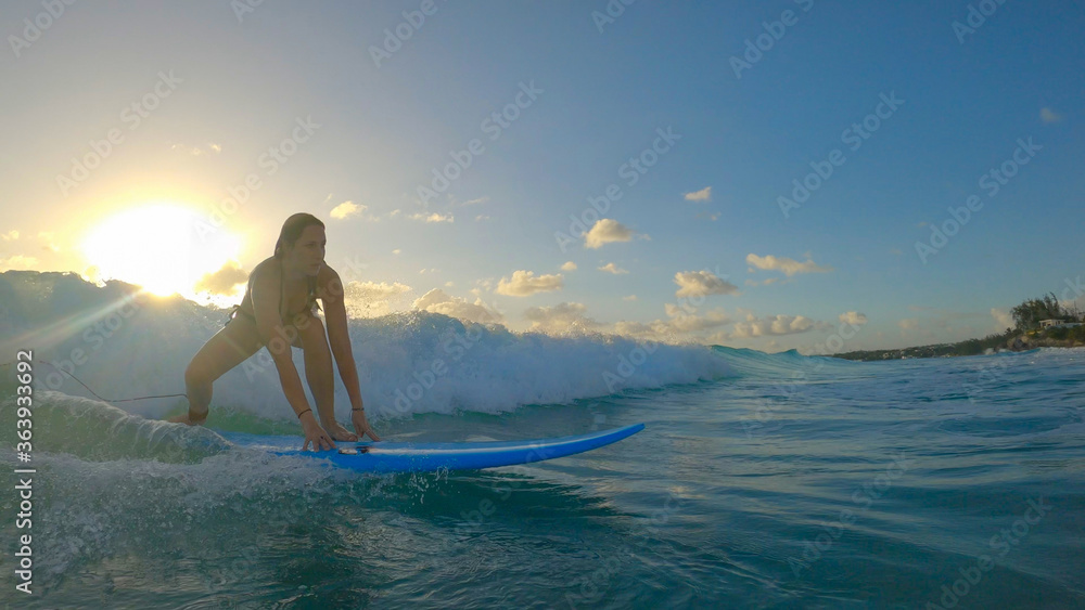 太阳耀斑：学习冲浪的女人站在长板上冲浪