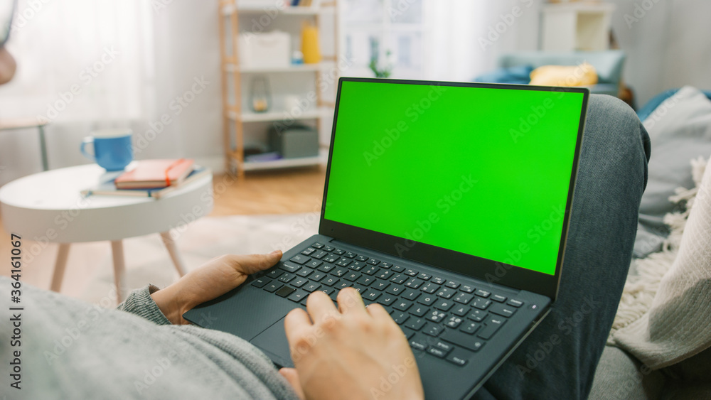 家里的男人躺在沙发上，用绿色实体屏幕笔记本电脑。男人用笔记本电脑Devi