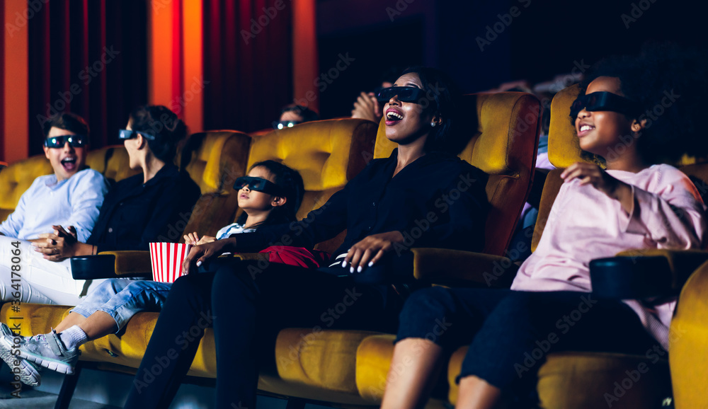 一群人在电影院里戴着3D眼镜看电影，饶有兴趣地看着屏幕，e