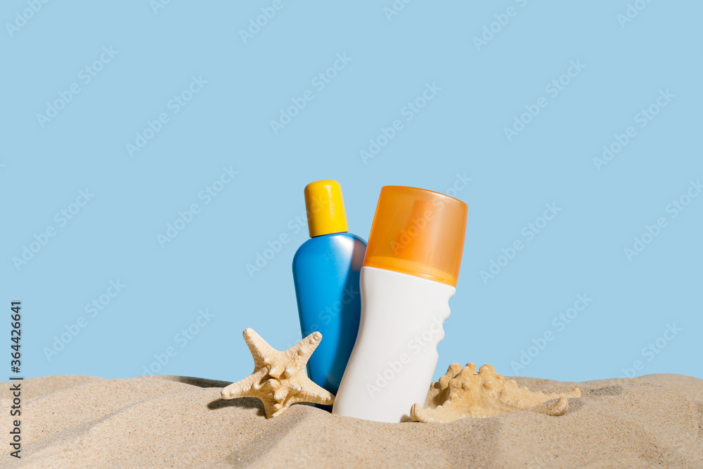 在彩色背景下的沙子上涂上几瓶防晒霜