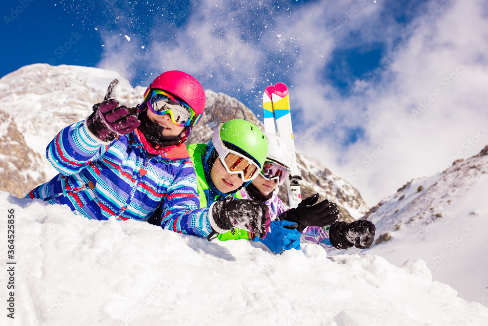 一群快乐的滑雪孩子男孩和女孩一起躺在雪地里，背景是山