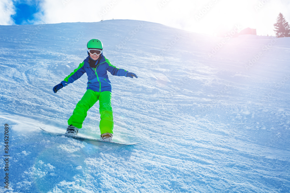 一个男孩在单板滑雪板上下坡的快速动作照片，从侧面用手和雪保持平衡