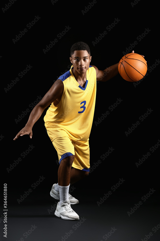 黑暗背景下的年轻非裔美国篮球运动员