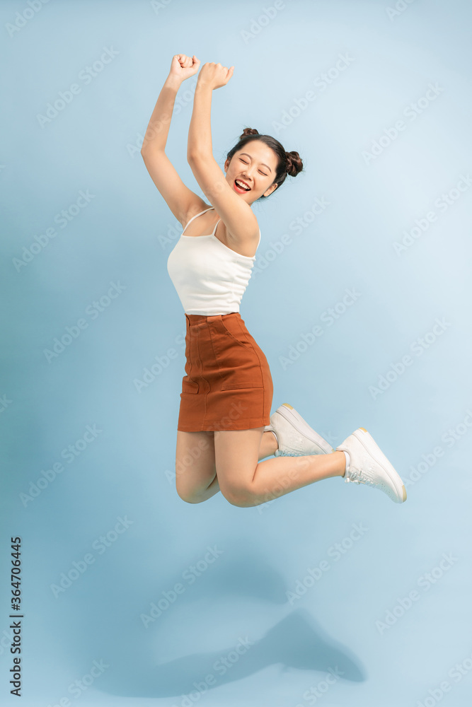 快乐的活跃女孩在空中跳跃，如果她是赢家，被隔离在蓝色背景上