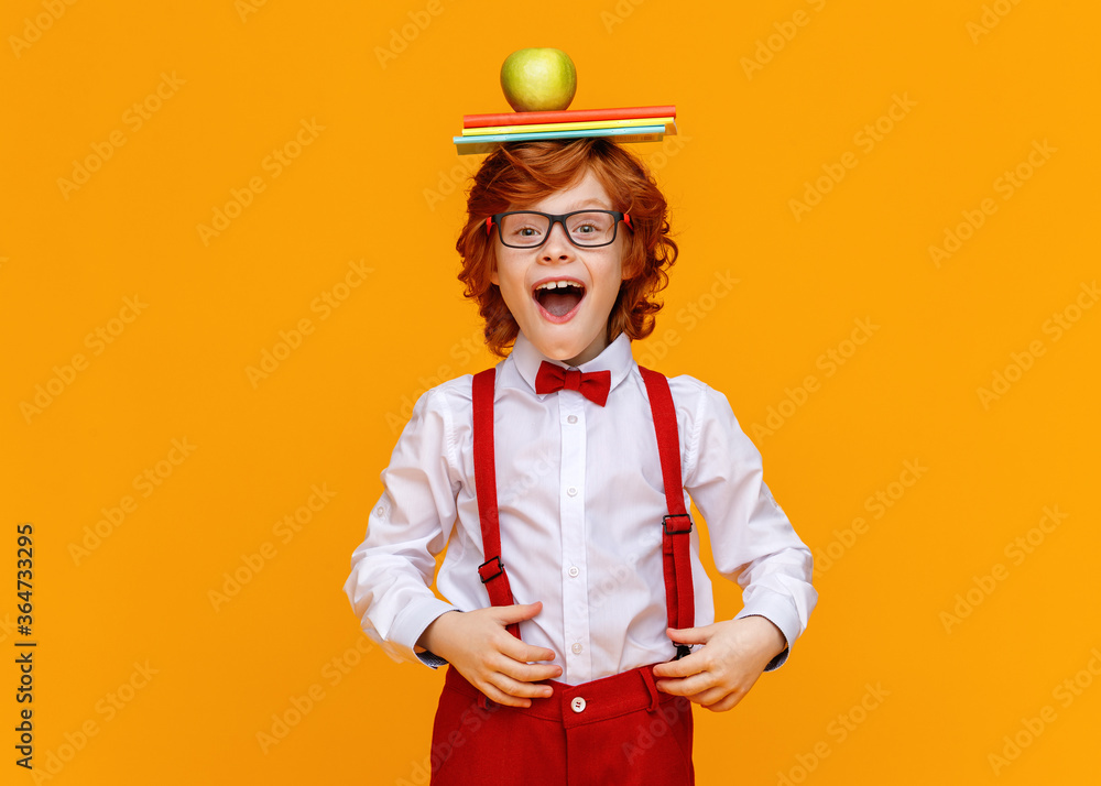 兴奋的小学生，头上戴着书和苹果。