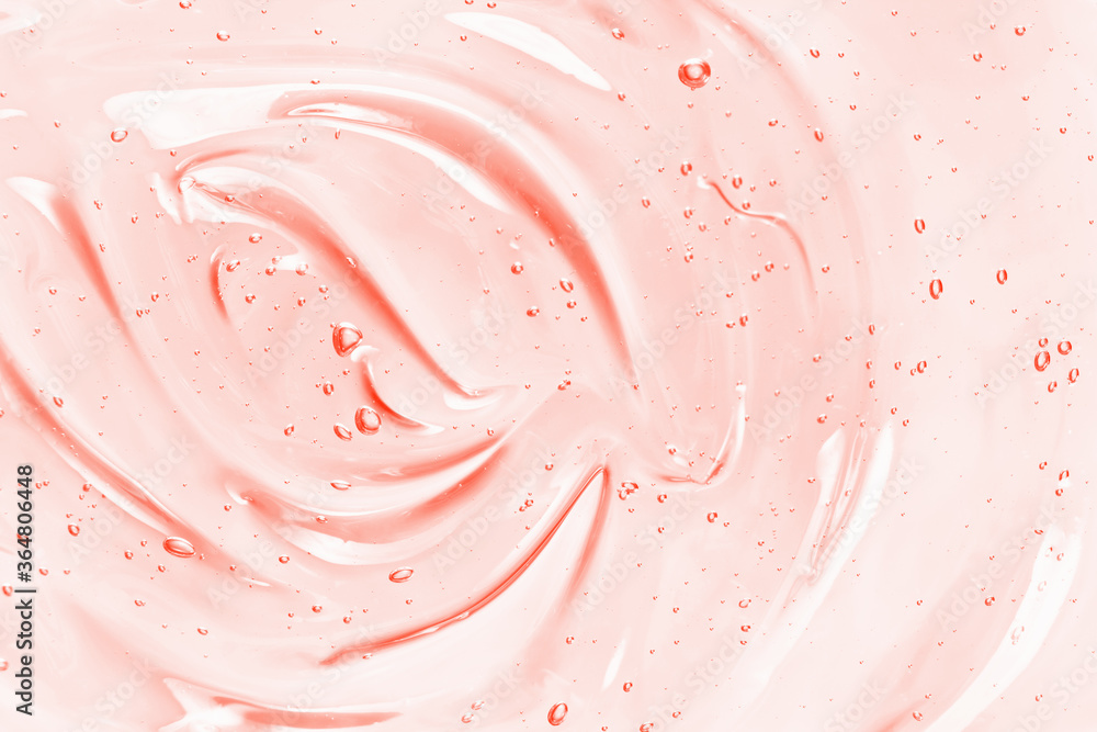 美容精华凝胶质地。粉红色透明护肤霜，泡沫背景。透明彩色cos