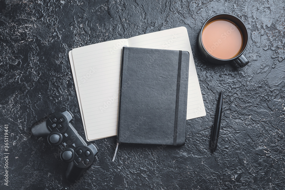 深色背景下带游戏手柄和一杯咖啡的笔记本