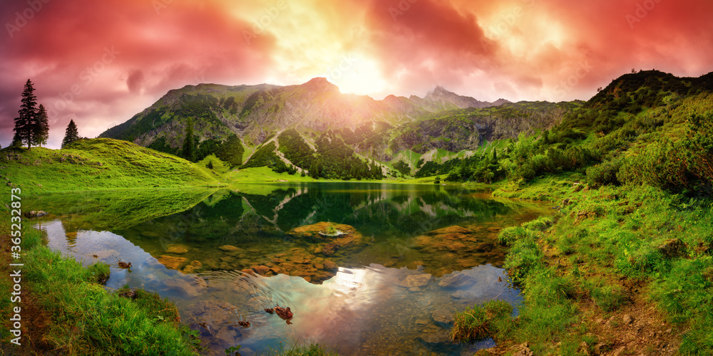阿尔卑斯山一个湖泊上的戏剧性日出，群山环绕，红云映在清澈的水中，p