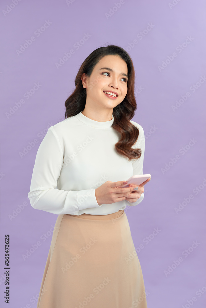 Photo of cheerful businesswoman smiling and using cellphone isolated over purple background
