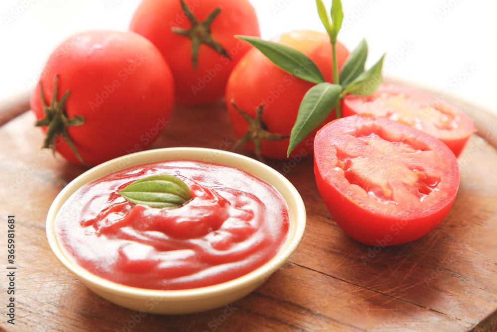 一碗番茄酱或番茄酱，配料放在木板上。
