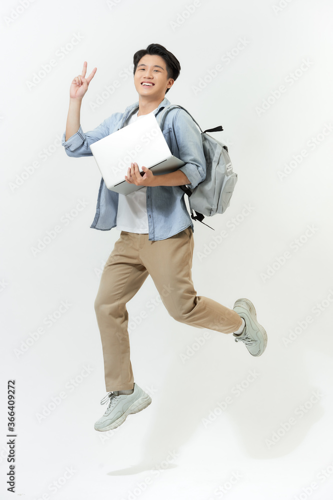 快乐跳跃亚洲程序员，彩色背景笔记本电脑