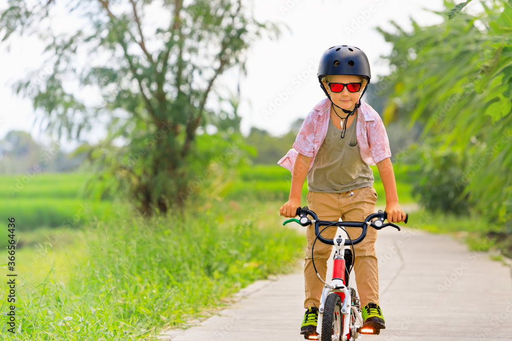 乡村自行车散步。戴着头盔和太阳镜的年轻骑手骑自行车。快乐的孩子玩得开心