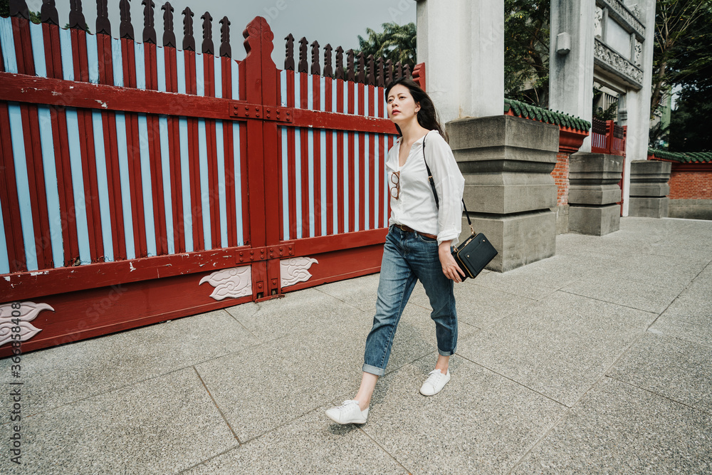 全长优雅的亚裔日本女游客走过历史建筑o的红门入口