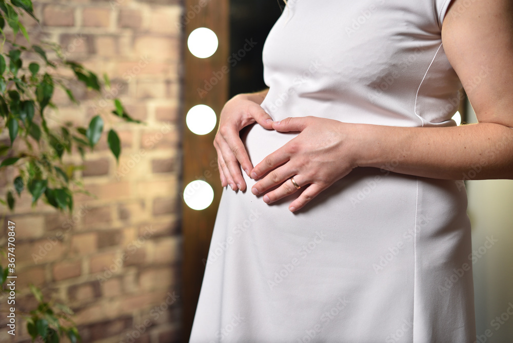 孕妇抱着肚子在砖墙背景上
