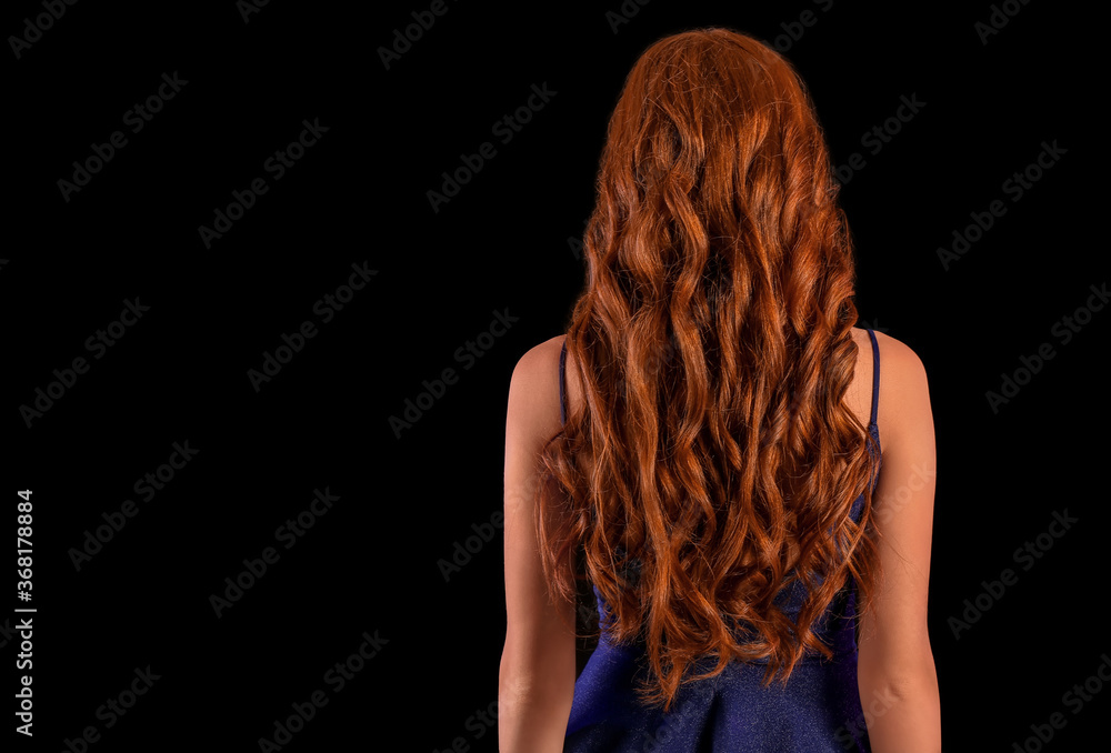 深色背景下美丽的年轻红发女人，后视图