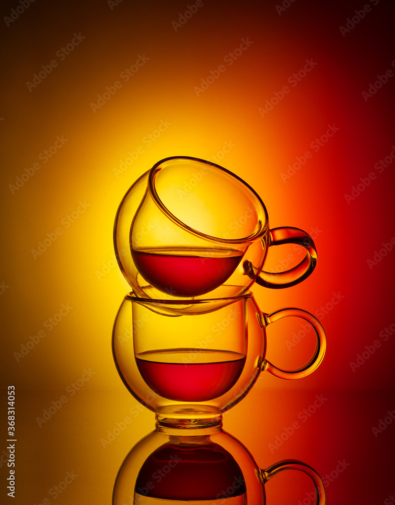 两杯黄色和红色背景的茶。茶的创意概念。