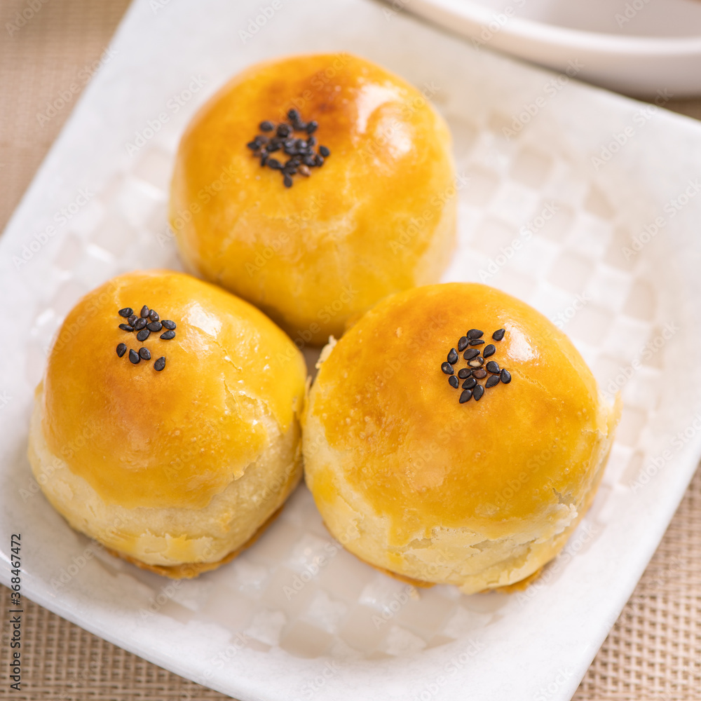Tasty baked egg yolk pastry moon cake for Mid-Autumn Festival on bright wooden table background. Chi