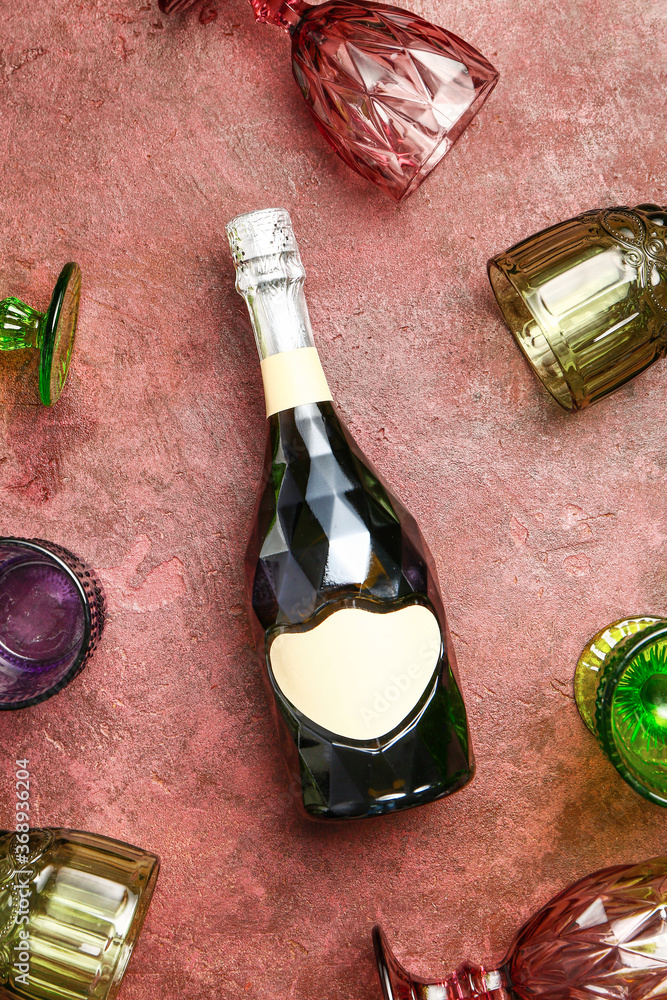一瓶香槟和彩色背景玻璃杯