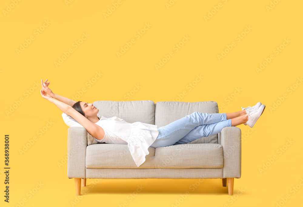 年轻女子在彩色背景下的沙发上放松