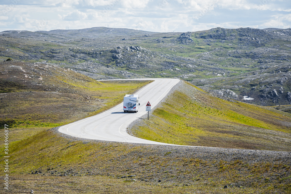 一辆旅行大篷车，又称露营车，行驶在前往挪威北部北开普省的风景优美的道路上