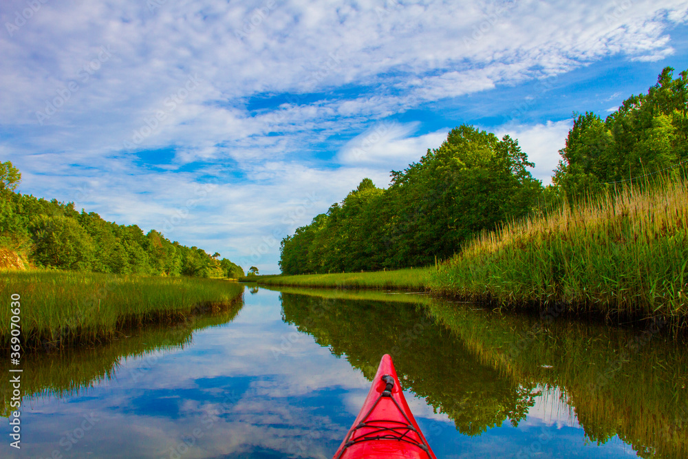 Kayaking on a narrow canal surrounded by reeds and vegetation. The water is calm and gives beautiful
