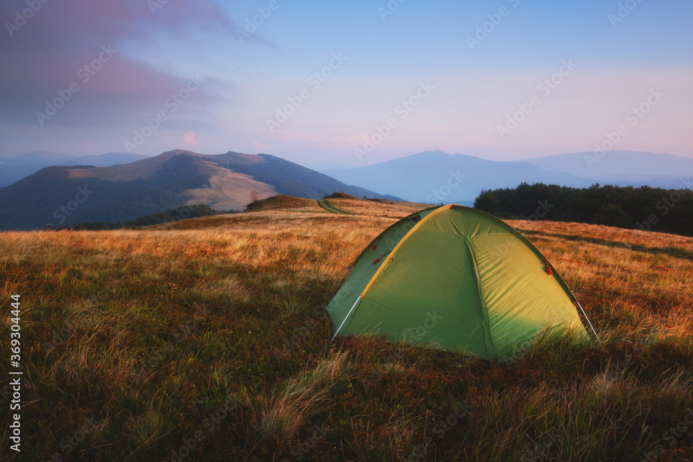 春日群山中的绿色帐篷。令人惊叹的黄昏高地。风景摄影