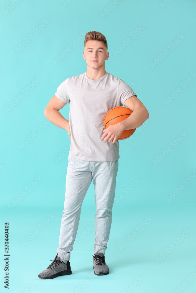 Young man with ball on color background