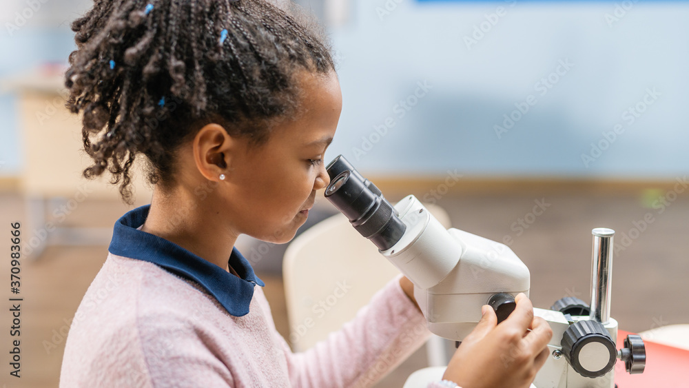 聪明的小女学生在显微镜下看的肖像。小学课堂剪辑