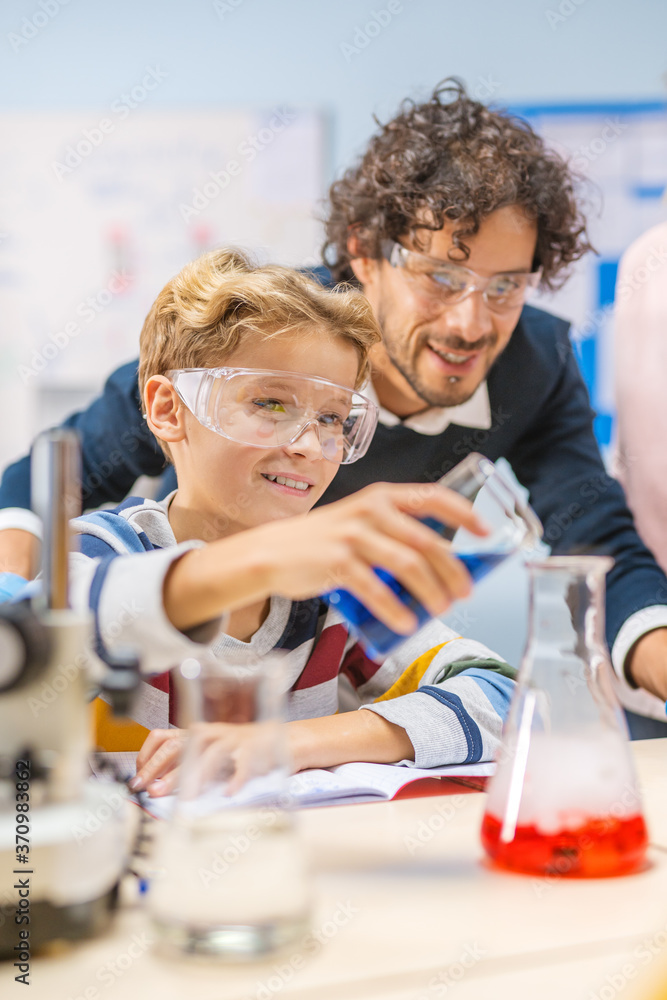 小学科学课堂：小男孩在烧杯中混合化学物质，热情的Hel老师