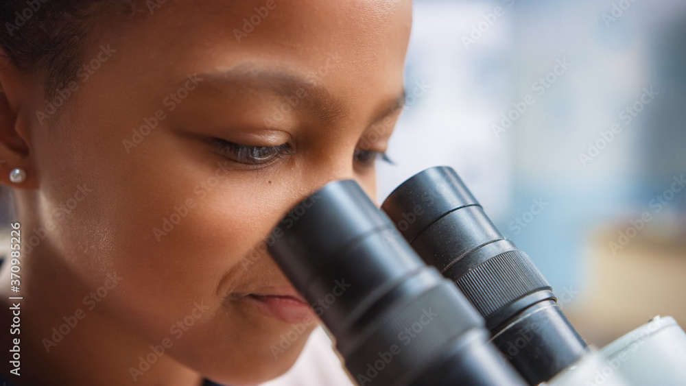 聪明的小女学生在显微镜下看的肖像。小学课堂剪辑