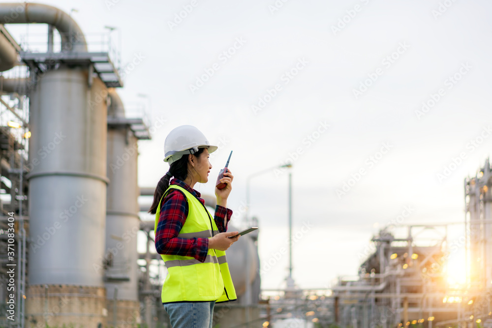 亚洲女技术员，工业工程师，使用对讲机，手持蓝图，在油厂工作
