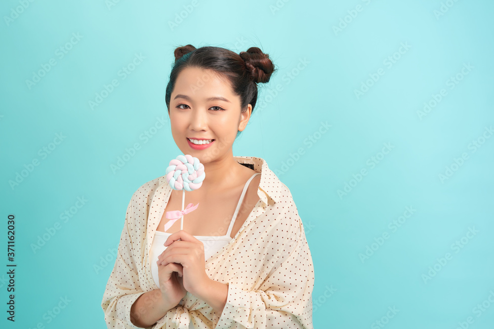 Teenager asian girl holding a lollipop over isolated blue background