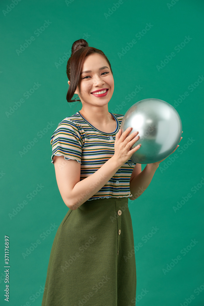 Beautiful young happy woman with smile, silver balloon on green background