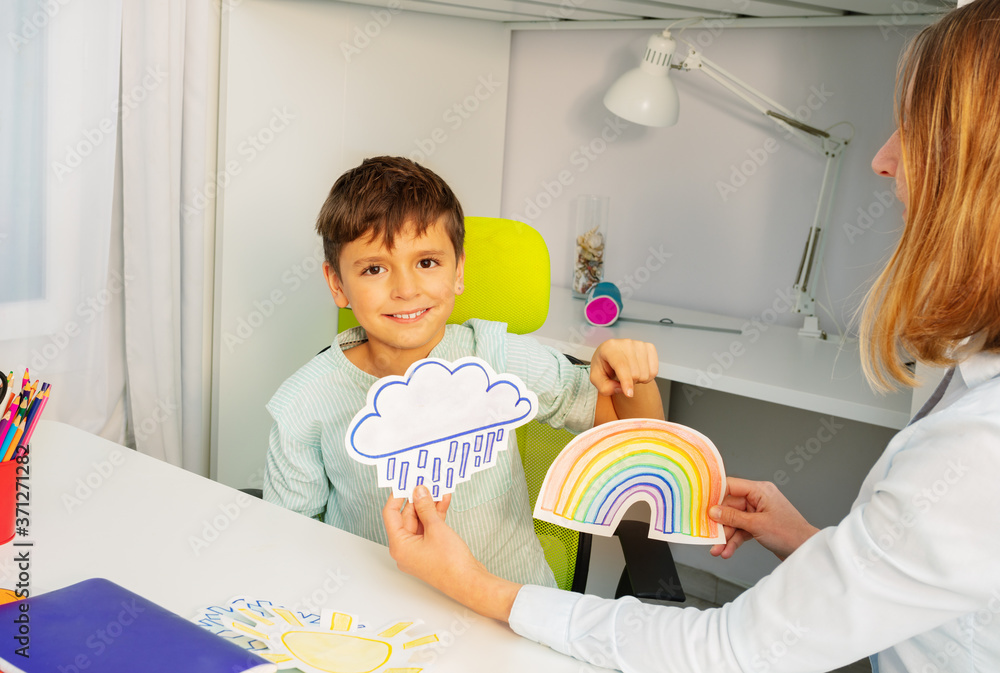 小男孩在aba发育治疗中坐着在彩虹和风暴两张牌之间选择