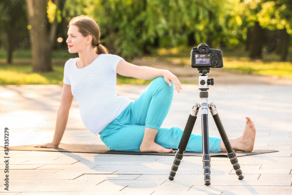 Young pregnant blogger recording sports video outdoors