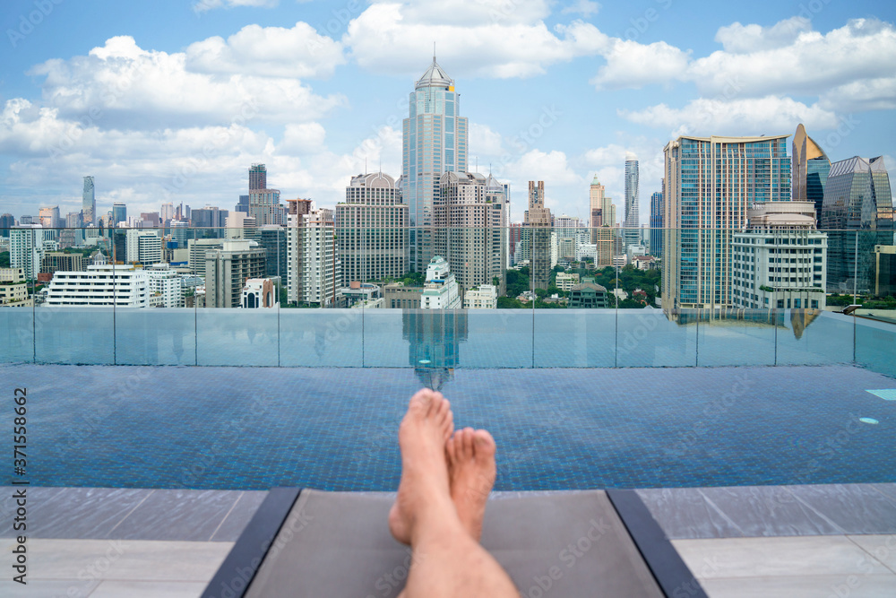 一名男子在曼谷市酒店屋顶游泳池放松和睡觉