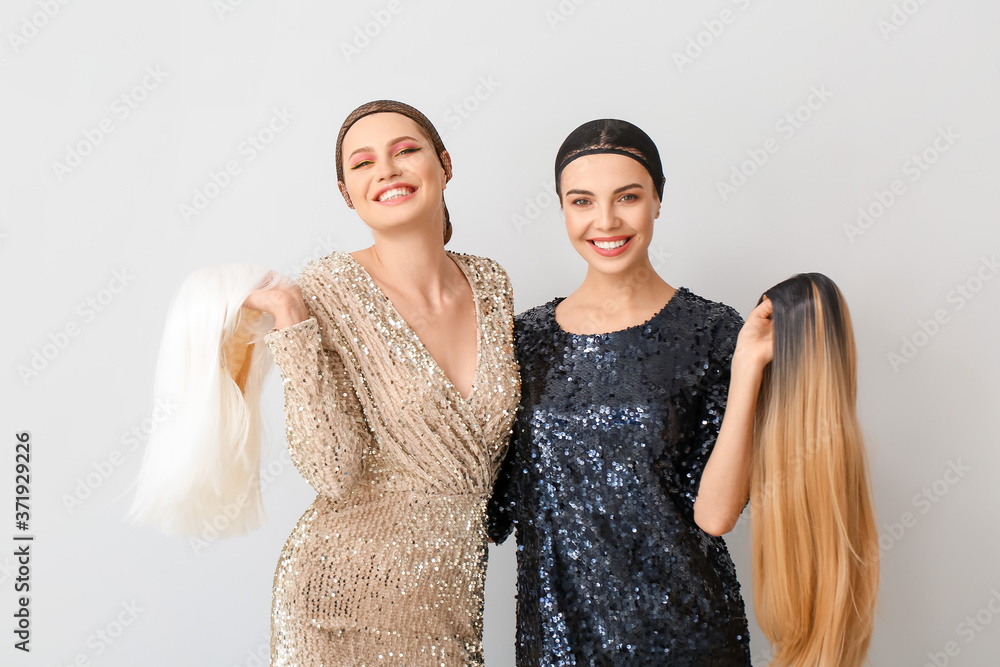 Beautiful young women with different wigs on light background