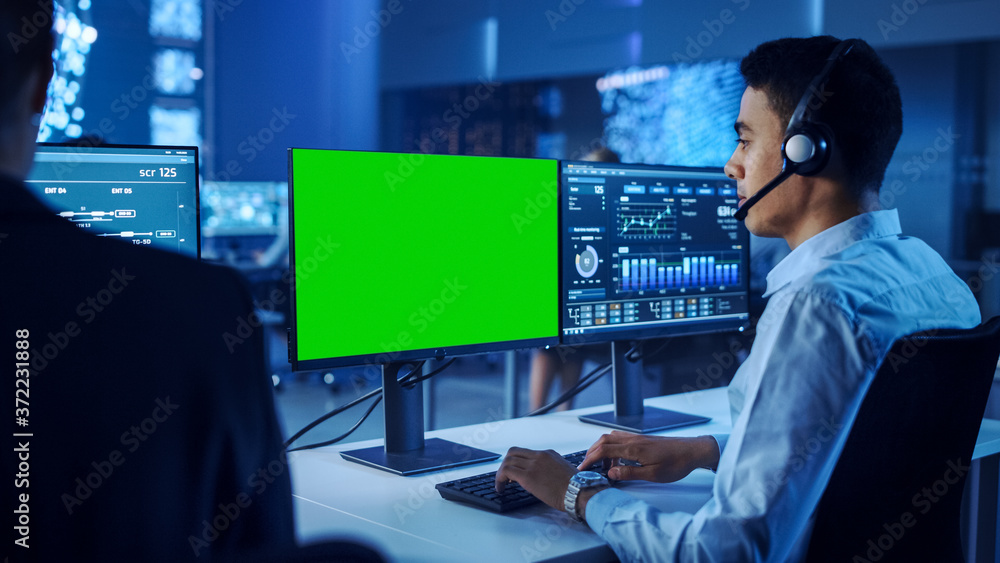 自信的男性数据科学家戴着头戴绿屏模板在个人电脑上工作