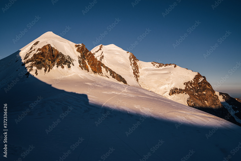 Sunset view of famous alpine peaks Pollux and Castor known as Gemini peaks, Valais, Switzerland. Alp