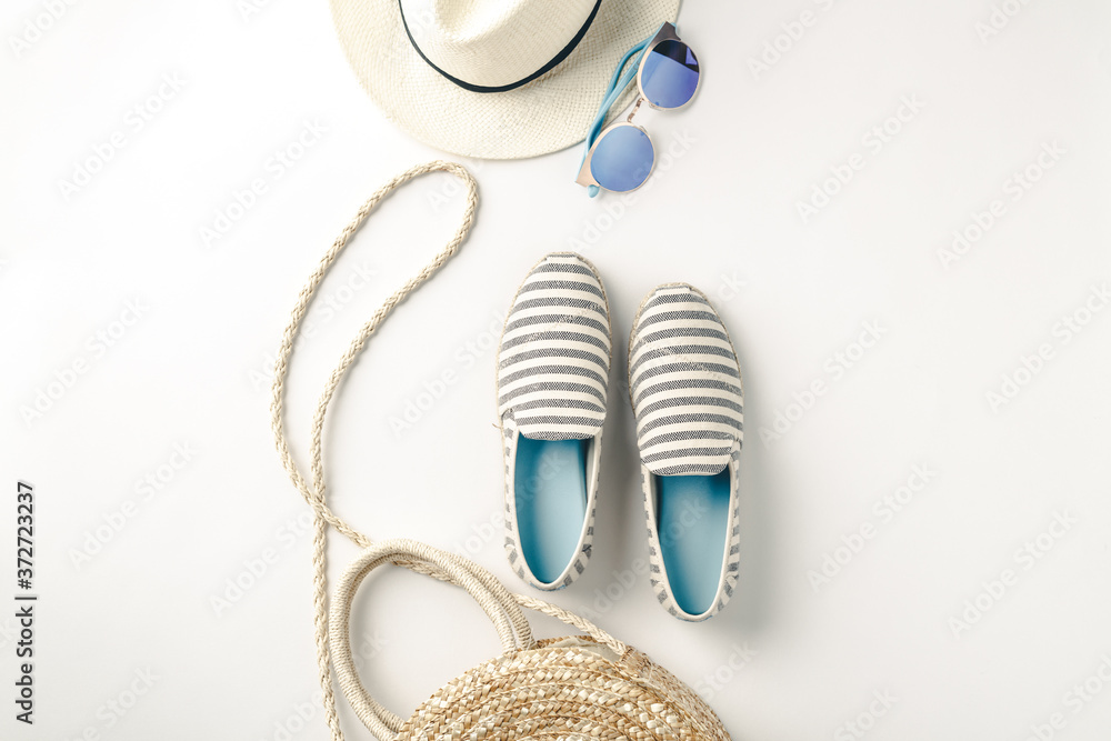 Flat lay traveler accessories on white background with straw hat, summer shoes, bag and sunglasses.
