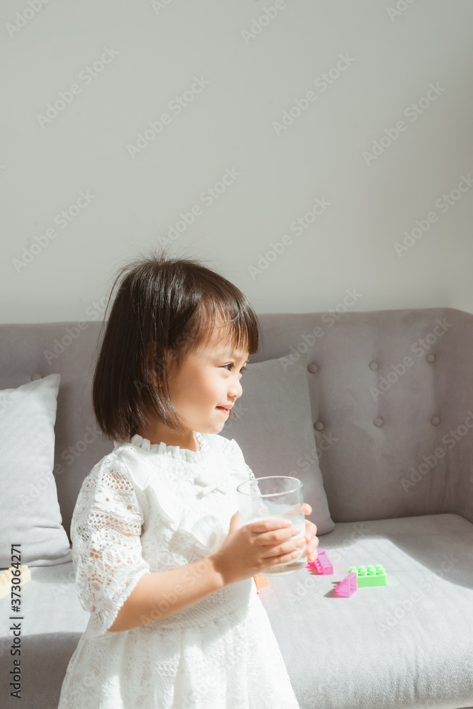 可爱的女孩在家里拿着一杯牛奶。