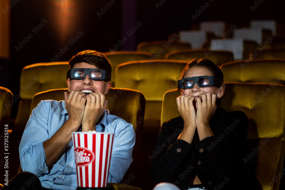 电影院里的男男女女戴着3D眼镜看电影。饶有兴趣地看着屏幕，e