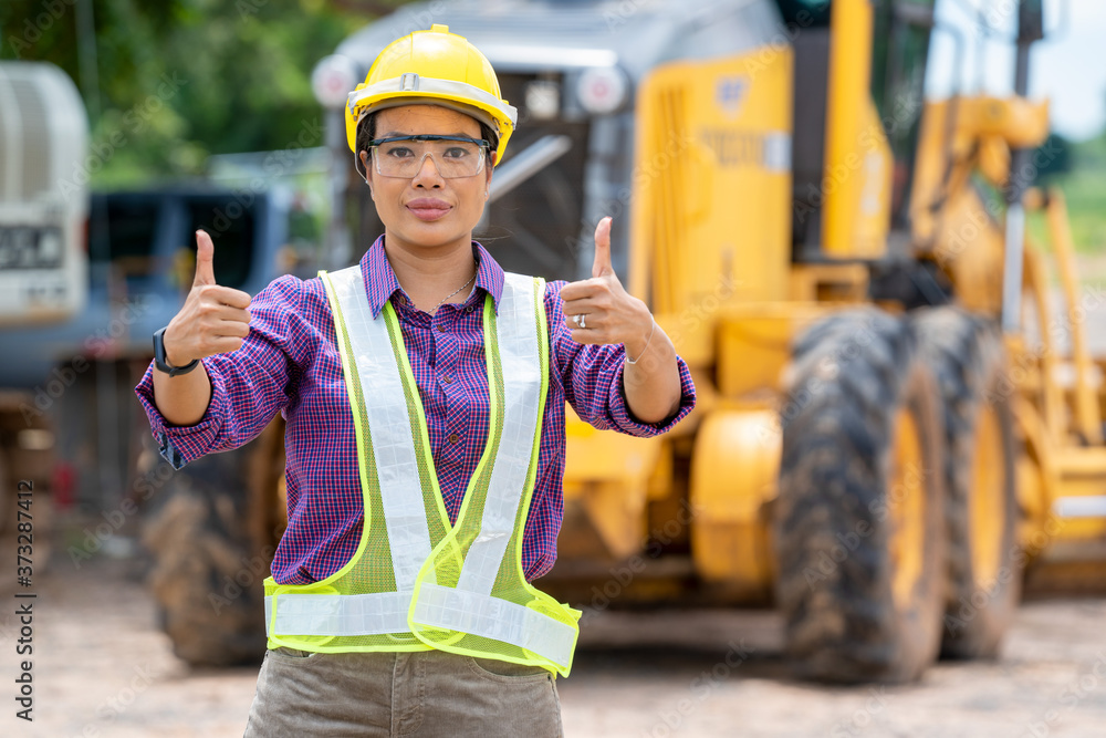 女工程师戴着头盔，在建筑施工现场竖起大拇指，施工
