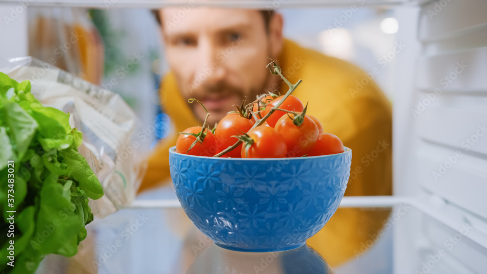 厨房冰箱里的摄像头：英俊的男人打开冰箱门，想拿一碗西红柿。男人P