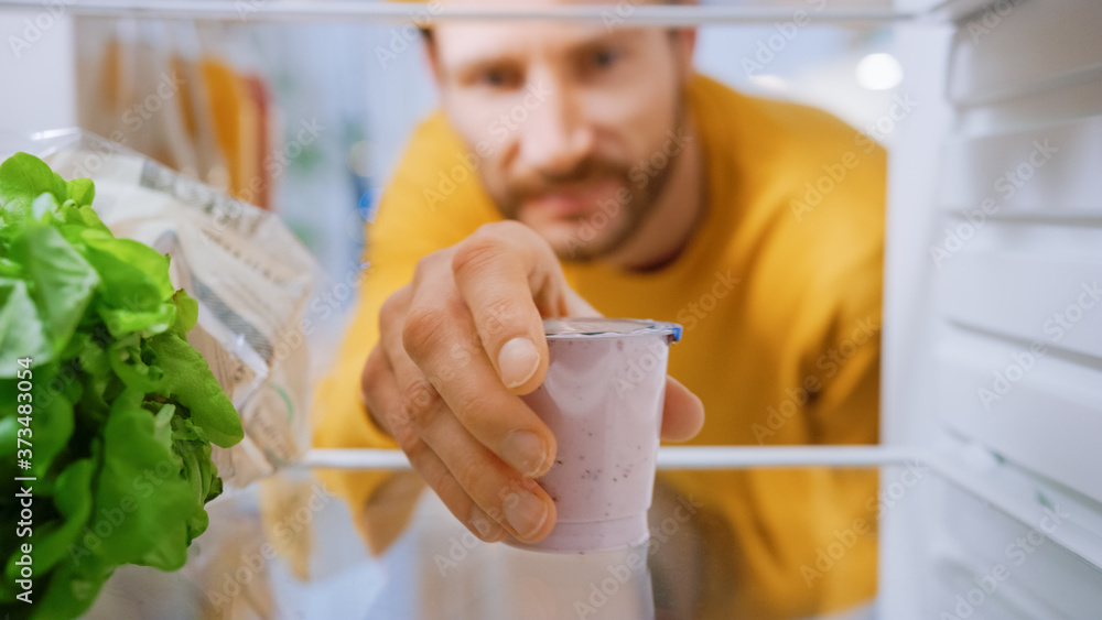 厨房冰箱里的摄像头：英俊的男人打开冰箱门，拿出酸奶。男人吃得健康。