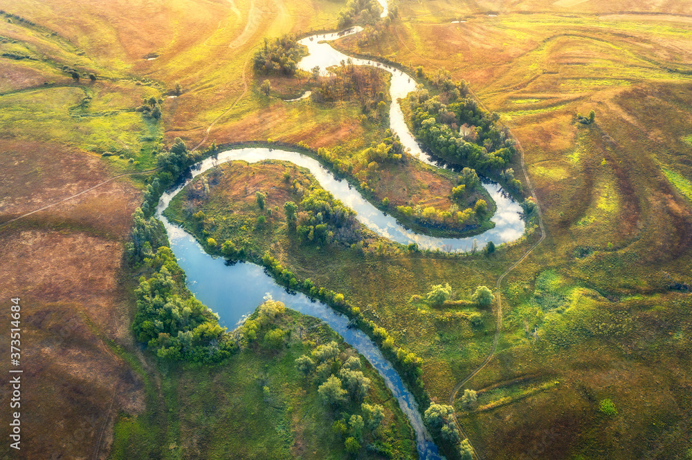 Aerial view of beautiful curving river at sunrise in summer. View from air. Turns of river, green me
