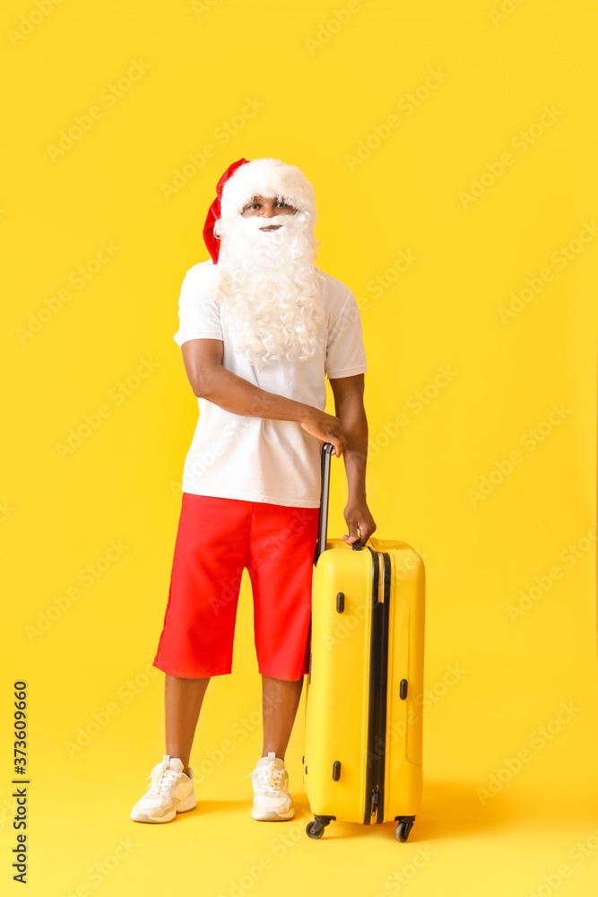 非洲裔美国圣诞老人，彩色背景行李箱。度假的概念