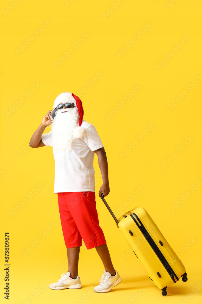 非洲裔美国圣诞老人，彩色背景行李箱。度假的概念