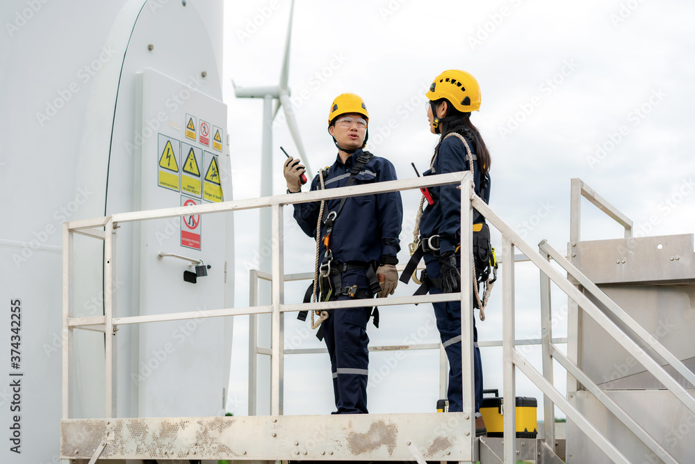 Asian man and woman Inspection engineers preparing and progress check of a wind turbine with safety 