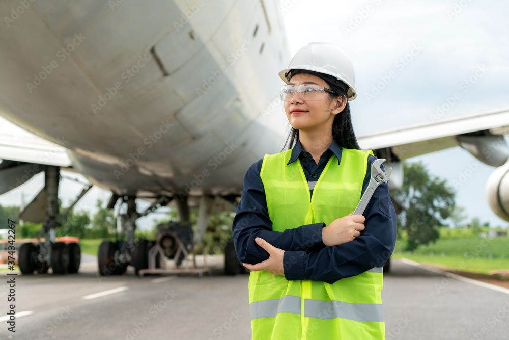 亚洲女工程师维修飞机手臂交叉，从repa手中拿着扳手在飞机前部
